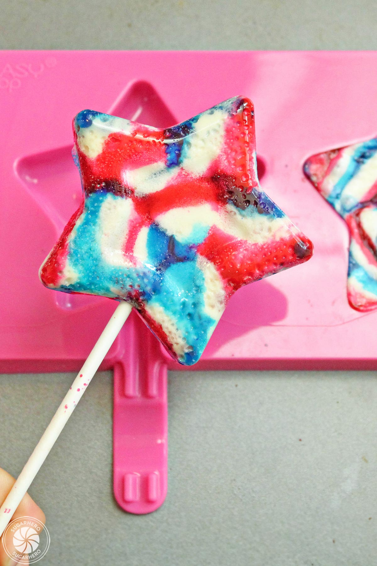 Easy Homemade Lollipops - swirled red, white, and blue star-shaped lollipop | From SugarHero.com