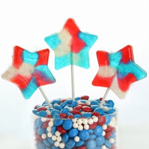 Three star shaped lollipops in a jar filled with candy.