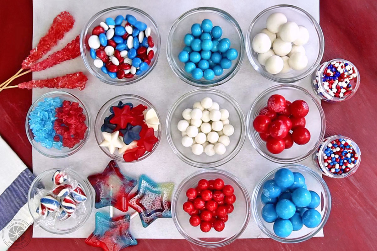 Fourth of July Layer Cake - assorted candies laid out in a flat lay, including red, white, and blue gumballs, M&Ms, gummies, and more | From SugarHero.com 