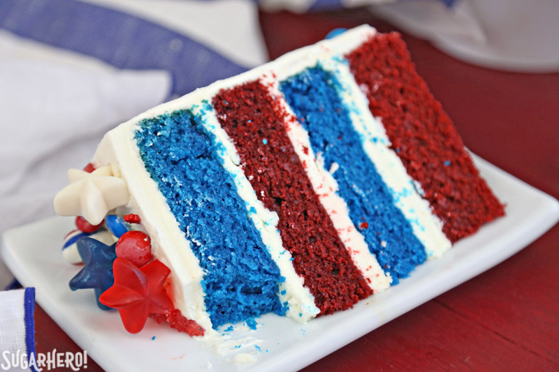 Fourth of July Layer Cake - close-up of slice of red and blue velvet cake with a bite taken out of it | From SugarHero.com 