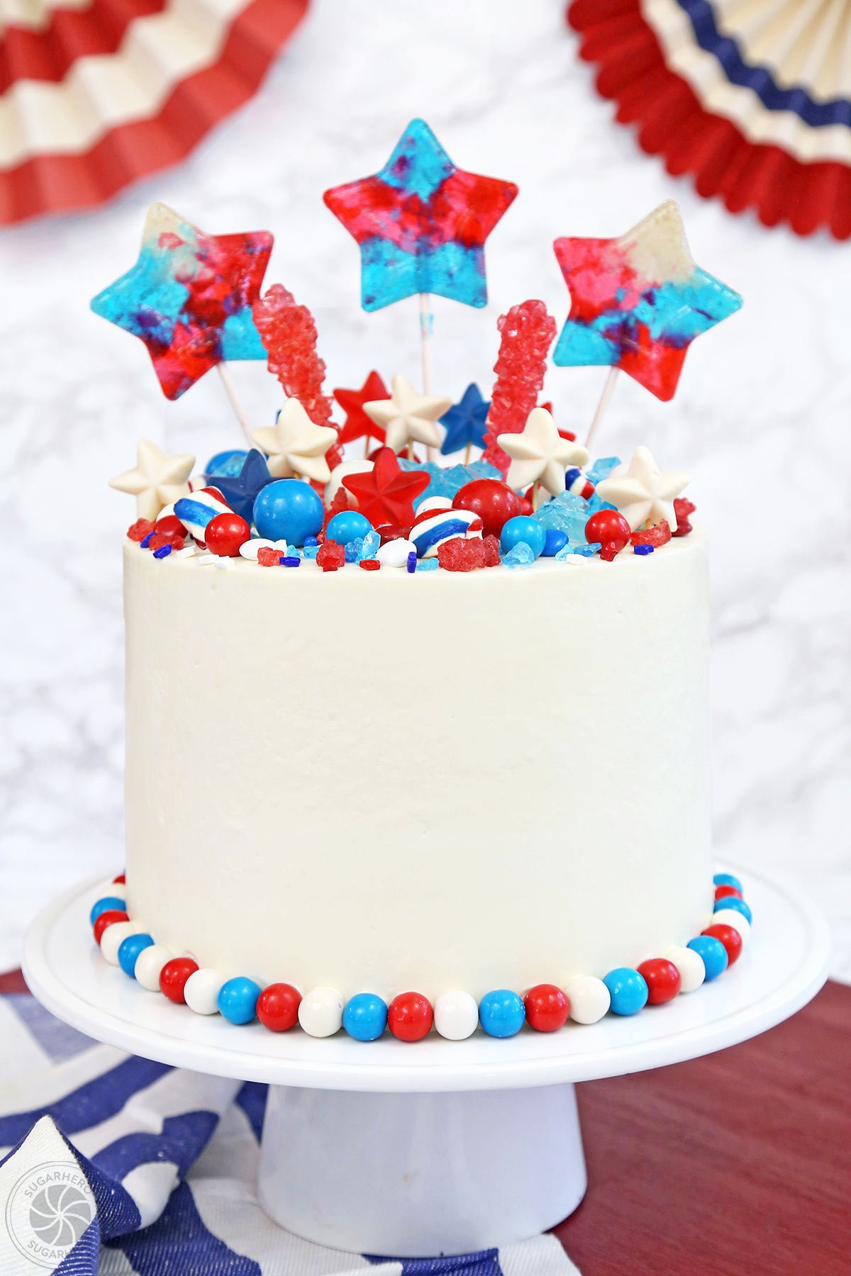 Fourth of July Layer Cake - tall layer cake with red, white, and blue candies on top | From SugarHero.com 