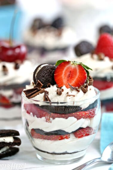 Mini Oreo Icebox Cake in a clear glass with a halved strawberry and mini Oreo on top.