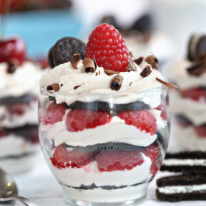 Close-up shot of an oreo icebox cake in a clear glass with a raspberry on top