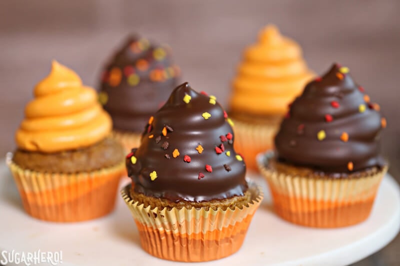 Pumpkin Spice Hi-Hat Cupcakes - Straight shot of multiple cupcakes with some covered in chocolate. | From SugarHero.com