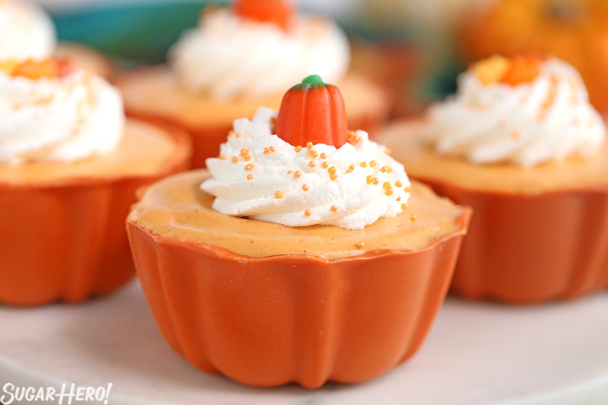 Pumpkin Spice Mousse Cups - This light and fluffy mousse is packed with fall flavor and made with real pumpkin, for an authentic pumpkin spice taste. It’s served in a cute edible candy bowl too! | From SugarHero.com Pumpkin Spice Mousse Cups - close-up of pumpkin spice mousse cup with candy pumpkin on top | From SugarHero.com