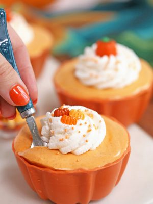 Pumpkin Pie Mousse Cup in orange candy bowl with spoon inserted ready to take a bite.