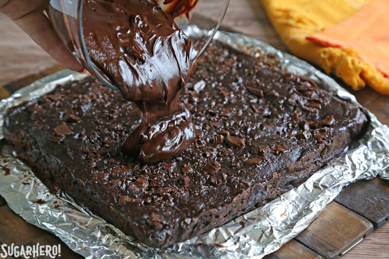2-Ingredient Pumpkin Brownies - pouring chocolate glaze on top of baked brownies | From SugarHero.com