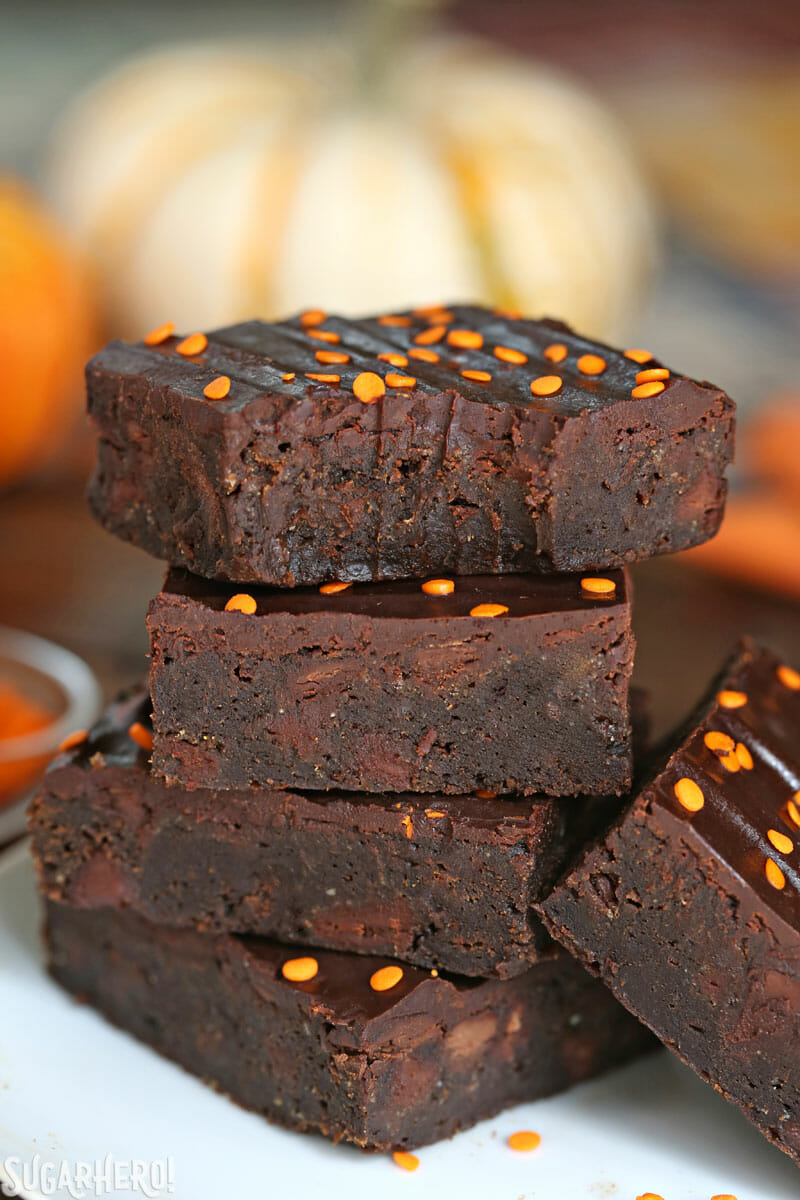 2-Ingredient Pumpkin Brownies - tall stack of brownies with a bite taken out of the one on top | From SugarHero.com