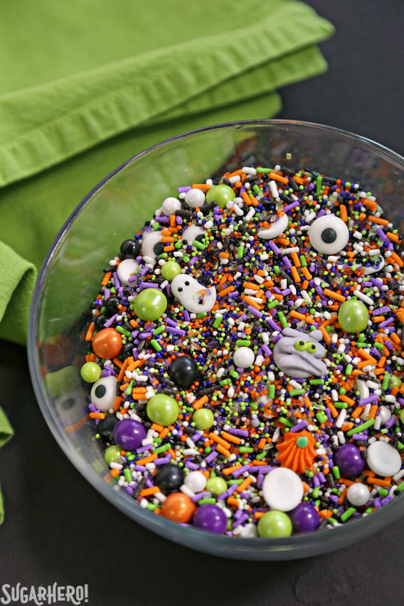 Halloween sprinkles in a bowl with a green cloth behind it
