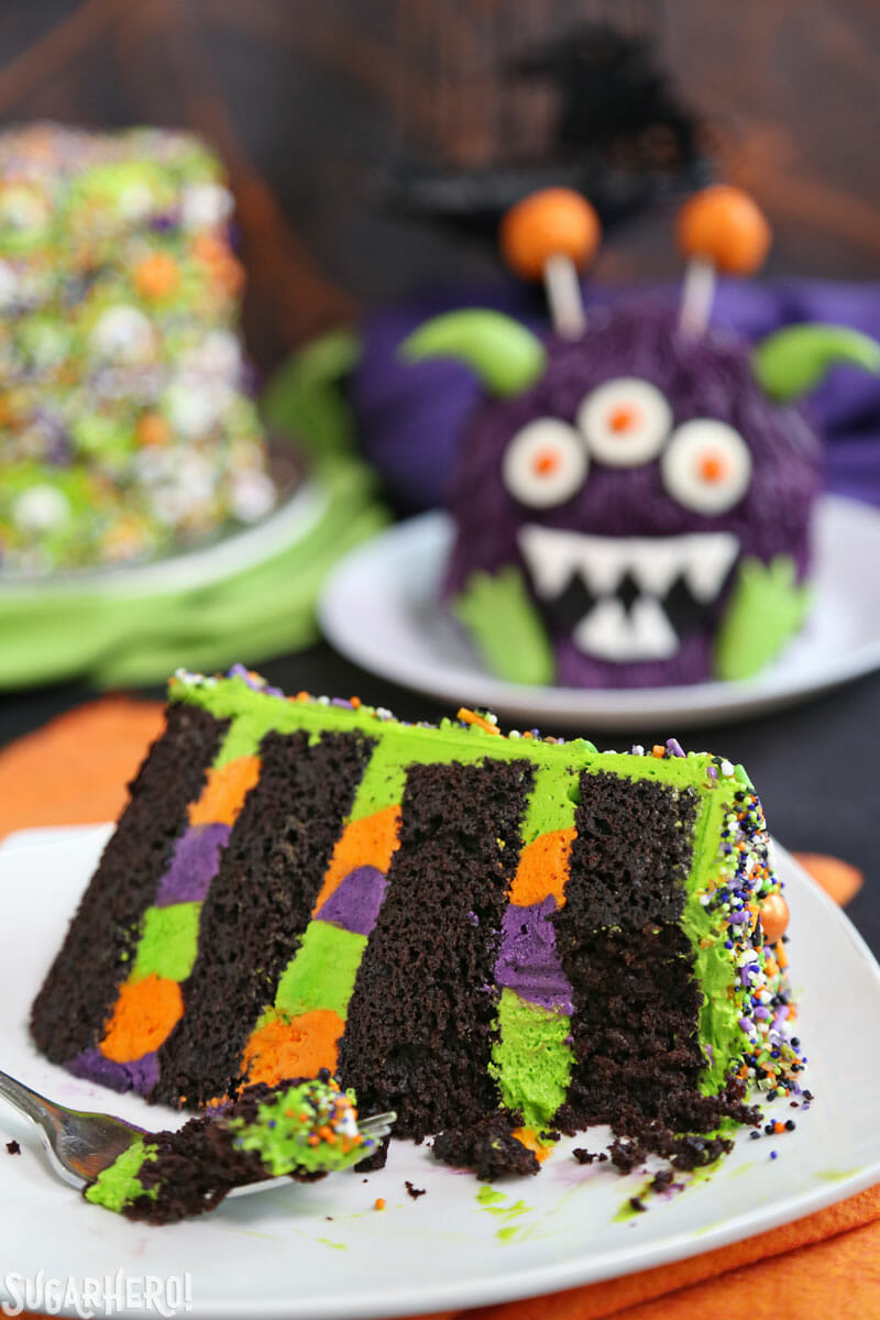 Slice of cake with a bite taken out of it and monster cake in the background 