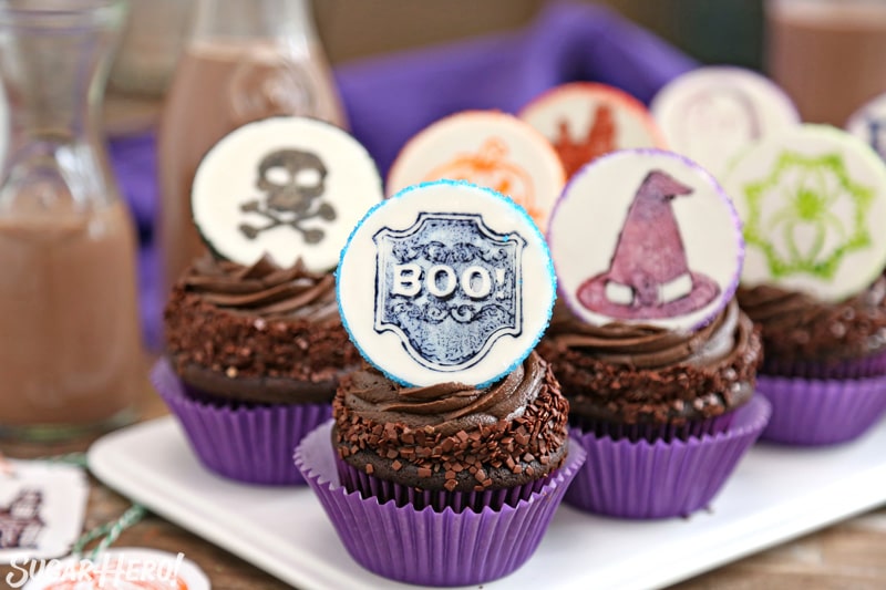 Stamped Halloween Cupcakes - group of chocolate cupcakes with cute Halloween-themed fondant circles on top | From SugarHero.com