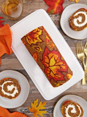 Overhead shot of patterned pumpkin roll with slices displayed around.
