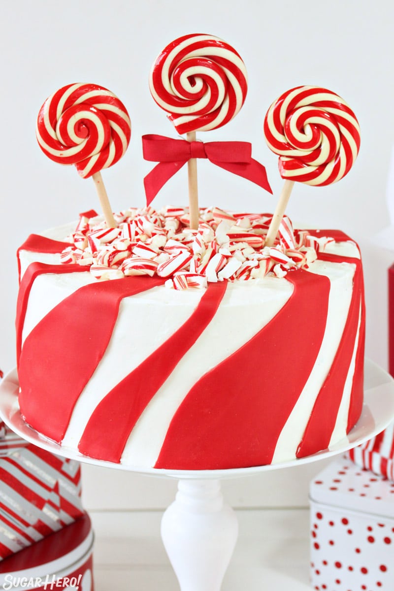 Candy Cane Chocolate Cake - Devil's food cake is paired with candy cane buttercream, and a cute red and white striped design. | From SugarHero.com Candy Cane Chocolate Cake - white cake with red fondant stripes, decorated with crushed candy canes and striped lollipops | From SugarHero.com