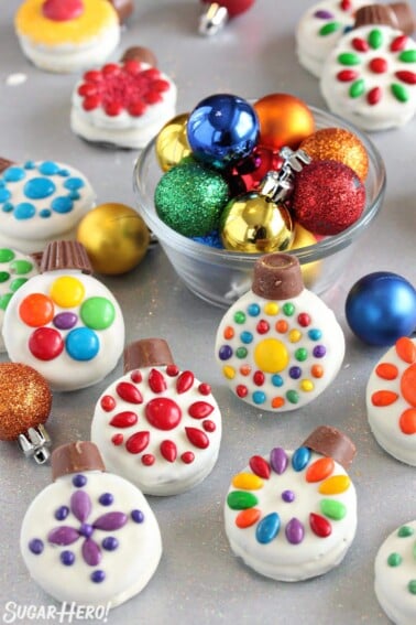 Oreo Cookie Christmas Ornaments on a glittery background with colorful ornaments in a bowl behind them.