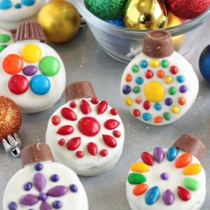 Oreo Cookie Christmas Ornaments on a glittery background with colorful ornaments in a bowl behind them.