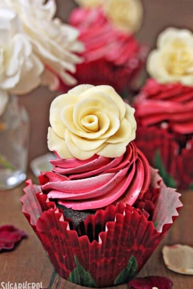 A chocolate cupcake with swirled frosting and a white chocolate rose on top.
