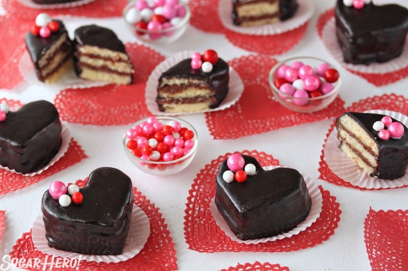 Nutella Pound Cake Petit Fours have big flavor in a small package! These sweet heart-shaped desserts are perfect for Valentine's Day or any special occasion. | From SugarHero.com Nutella Pound Cake Petit Fours - A mix of cut and whole petit fours with pink and red decorative candy on top. | From SugarHero.com