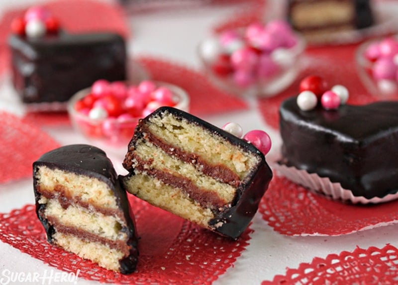 Nutella Pound Cake Petit Fours have big flavor in a small package! These sweet heart-shaped desserts are perfect for Valentine's Day or any special occasion. | From SugarHero.com Nutella Pound Cake Petit Fours - A petit four cut in half. Layers of cake and Nutella with decorative candy on the top. | From SugarHero.com