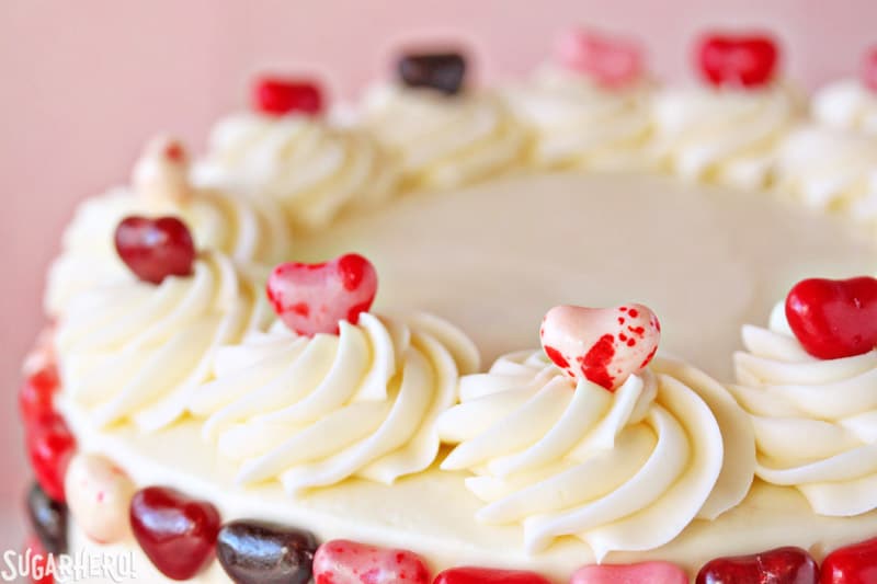 Sky-High Pink and Red Velvet Cake - Top of cake displayed with heart shape candies on swirls of frosting. | From SugarHero.com 