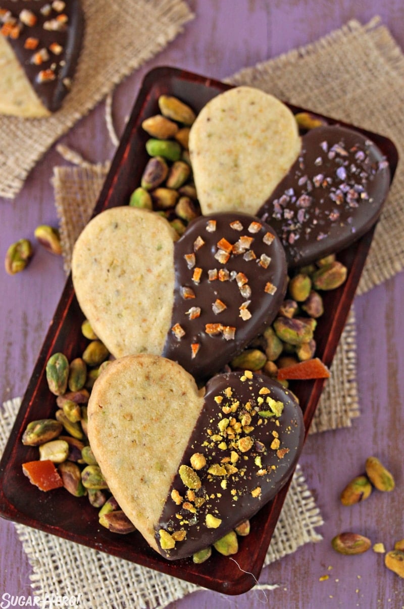 Pistachio Shortbread Cookies - Three cookies displayed on a tray with pistachios. | From SugarHero.com 