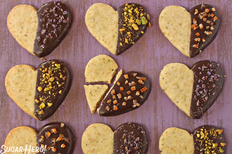 Pistachio Shortbread Cookies - 9 shortbread cookies displayed in rows of three. One of the cookies is broke into three pieces. | From Sugarhero.com 