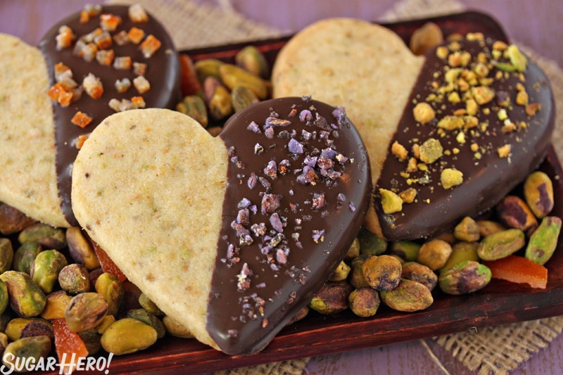 Pistachio Shortbread Cookies - Three cookies displayed on a tray with pistachios. | From SugarHero.com 