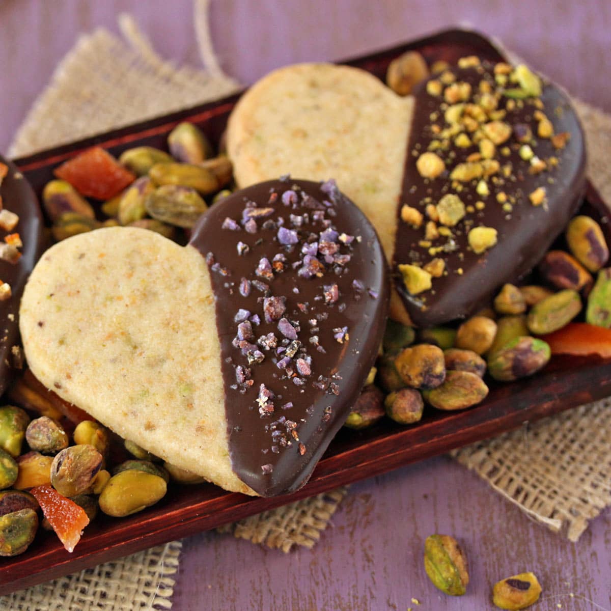 Close up of 3 Pistachio Shortbread Cookies on a bed of pistachios.