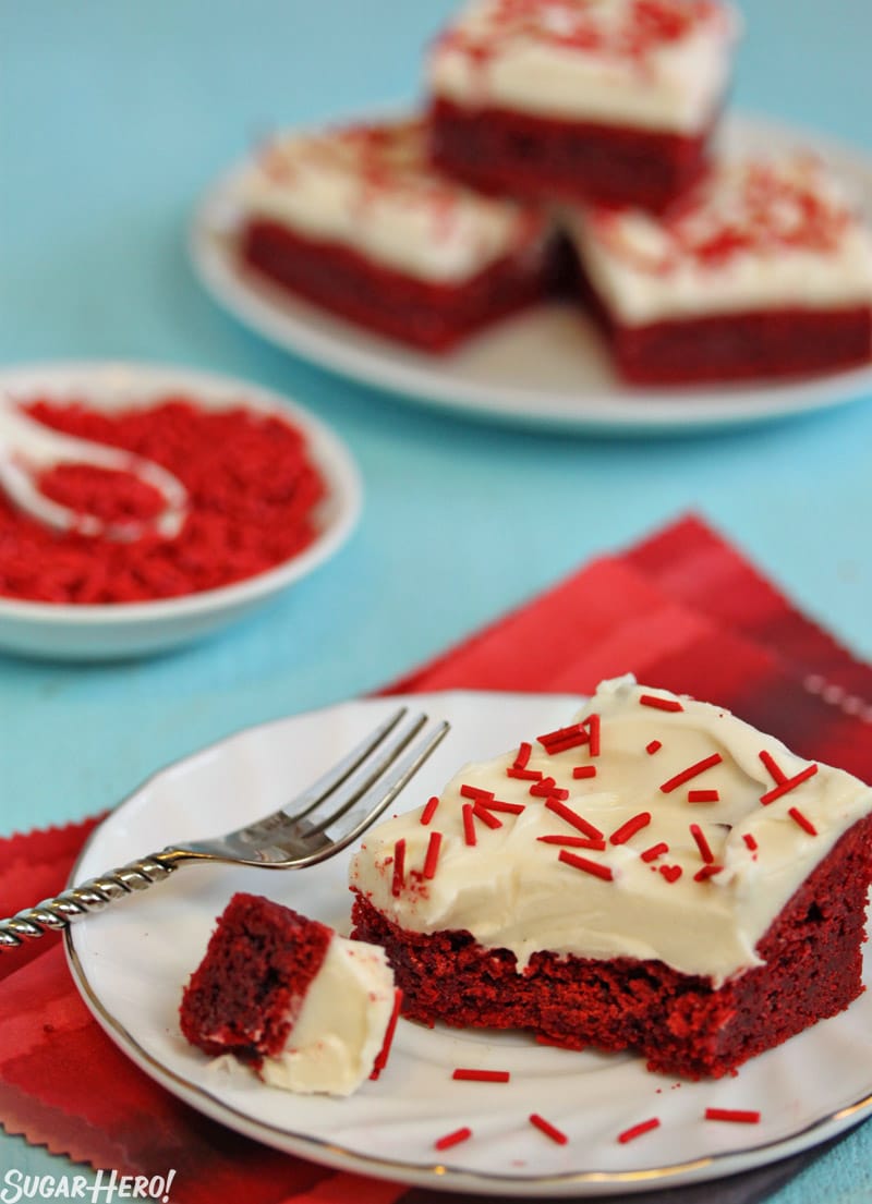 These Red Velvet Bars have the great taste of red velvet cake, in a portable cookie bar! | From SugarHero.com Red Velvet Bars - A Red Velvet Bar with a bite taken out of it. Homemade Sprinkles on top. | From SugarHero.com