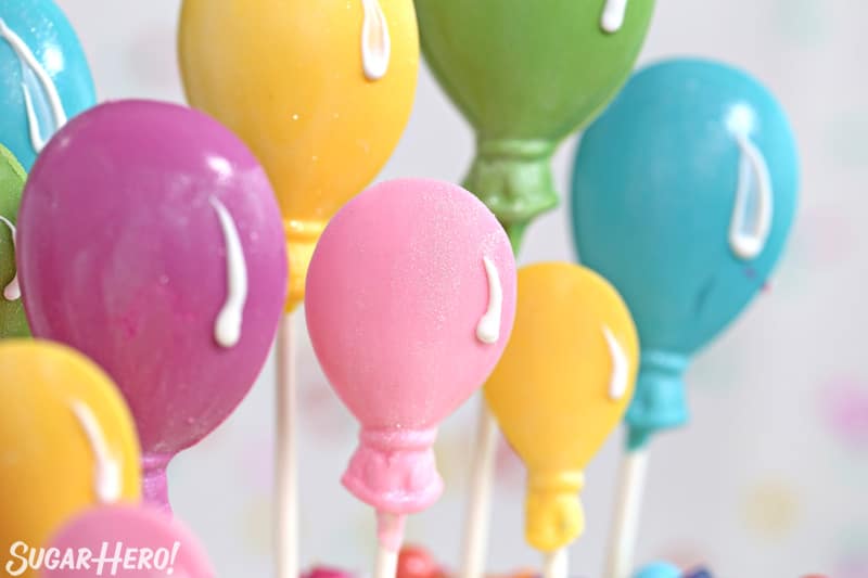 Close-up of candy balloon lollipops on top of Striped Buttercream Balloon Cake.