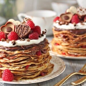 2 Chocolate Raspberry Mini Crepe Cakes on gold edged plates next to gold forks.