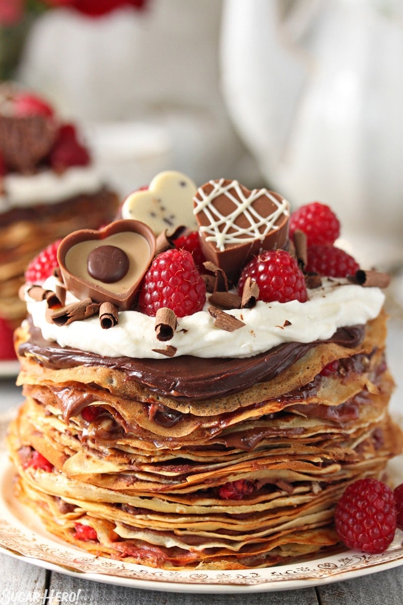 Chocolate Raspberry Mini Crepe Cakes - A single cake with heart shaped chocolates and raspberries on top.  | From SugarHero.com