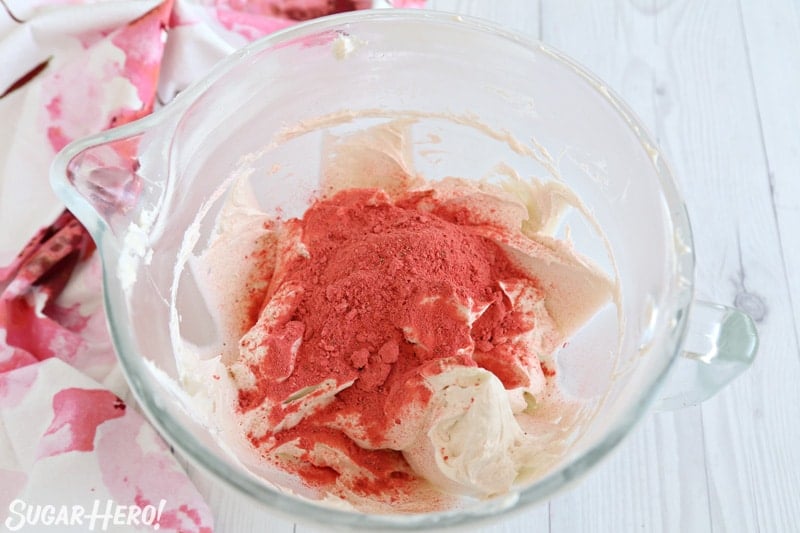 Strawberry Buttercream Frosting - freeze-dried strawberry powder scattered on top of white frosting in bowl | From SugarHero.com
