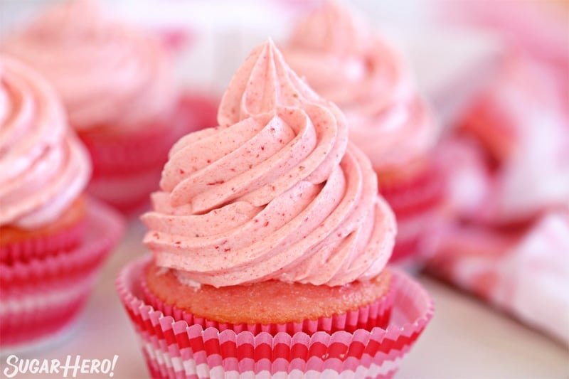 This Strawberry Buttercream is incredible! With a smooth, creamy texture and bright fresh strawberry flavor, it's going to be your new favorite frosting to put on everything! | From SugarHero.com Strawberry Buttercream Frosting - close-up of pink strawberry frosting swirl on a cupcake | From SugarHero.com
