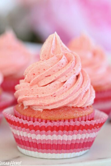 Close up of cupcake frosted with strawberry buttercream in a pink cupcake liner.