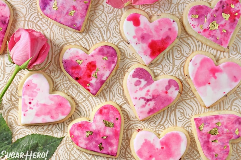 Watercolor Rose Sugar Cookies - Sugar cookies displayed on a patterned background with a rose. | From SugarHero.com 