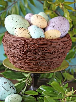 Easter Nest Cake on a green cake stand surrounded by greenery.
