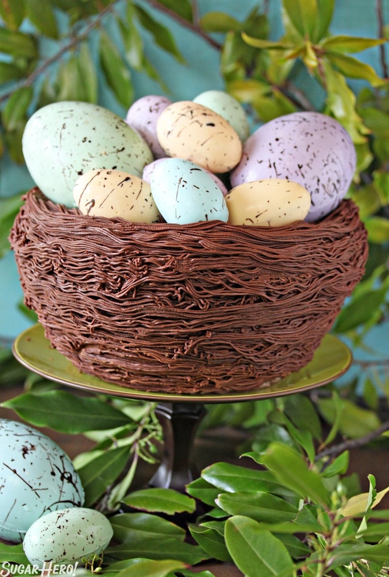 Easter Nest Cake on a green cake stand surrounded by greenery.