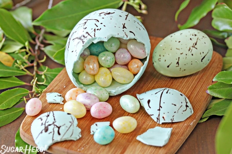 Chocolate egg that is broken with egg shaped candies spilling out.