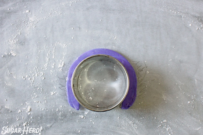 Wrapping a strip of purple fondant around a circular cookie cutter