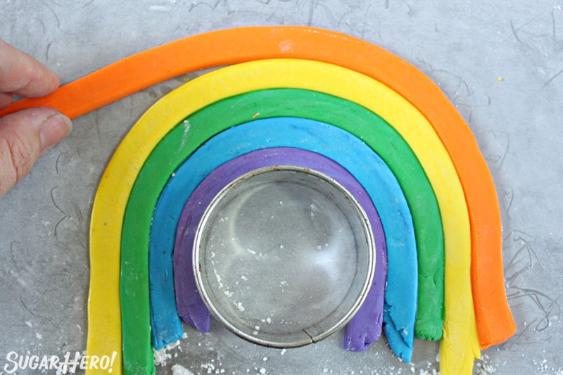 Adding a strip of orange fondant to the outside of the fondant rainbow cake topper