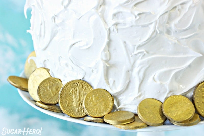 Close-up of edible chocolate gold coins around the base of the rainbow cake