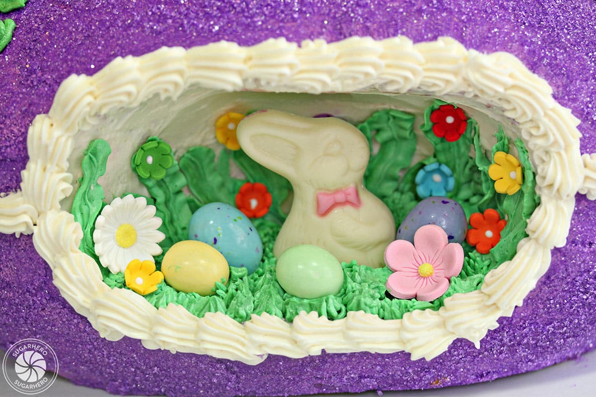 Close-up of the panoramic scene in the center of an Easter egg cake, featuring a white chocolate rabbit and chocolate eggs