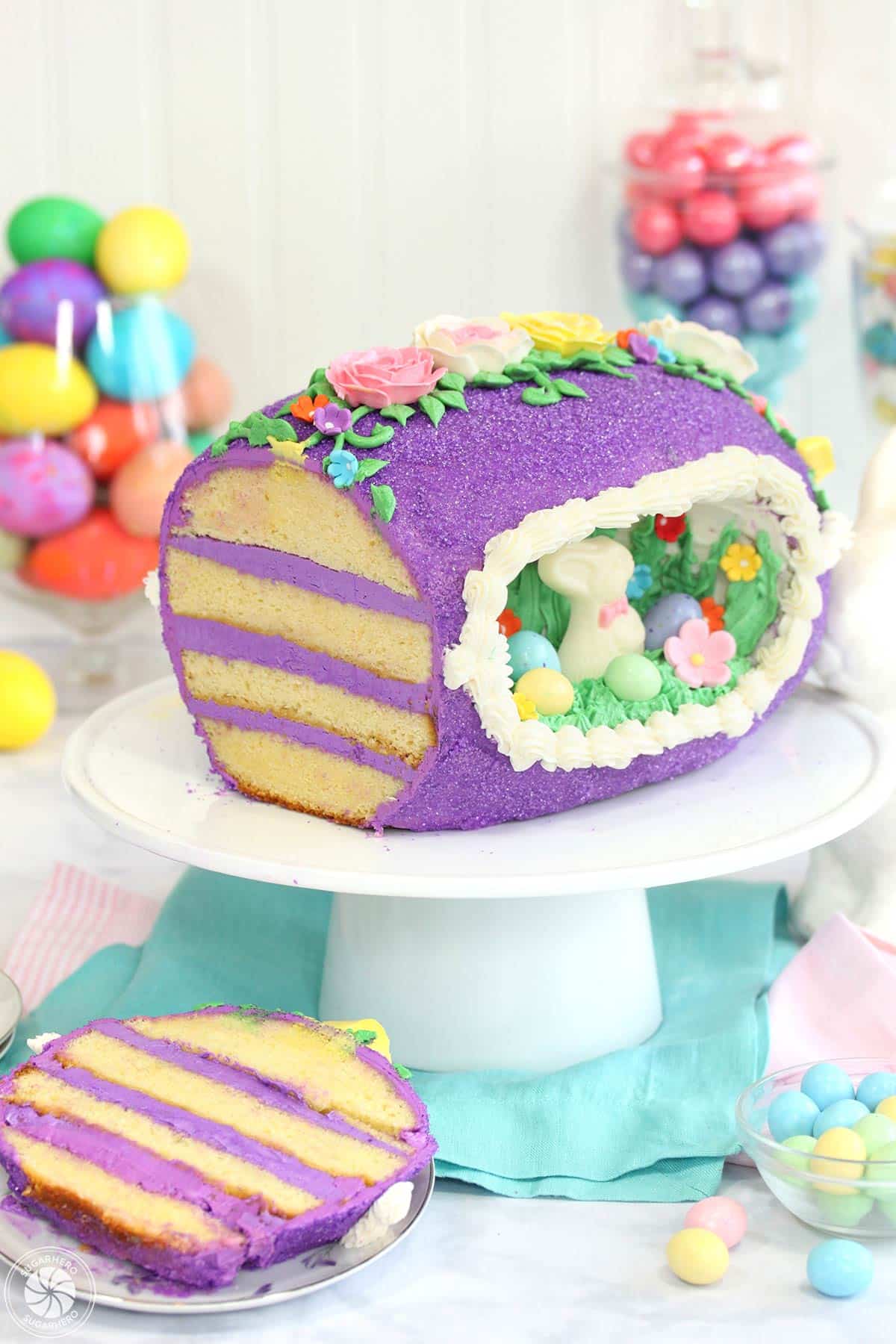 Sugar Easter egg cake, with a slice taken out of it and resting on a plate near the base of a cake stand