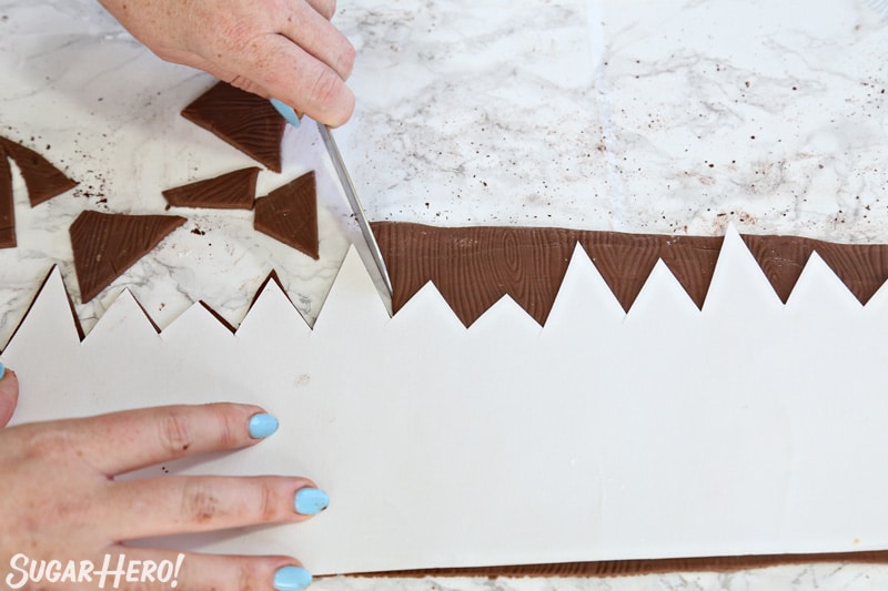 Cutting the top of the brown fondant strip to look like a jagged fence