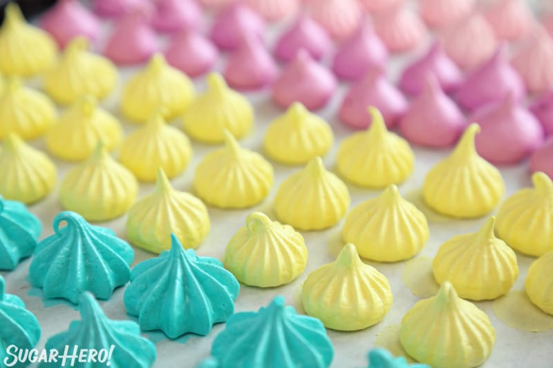 Colorful baked meringue kisses lined up on a baking sheet