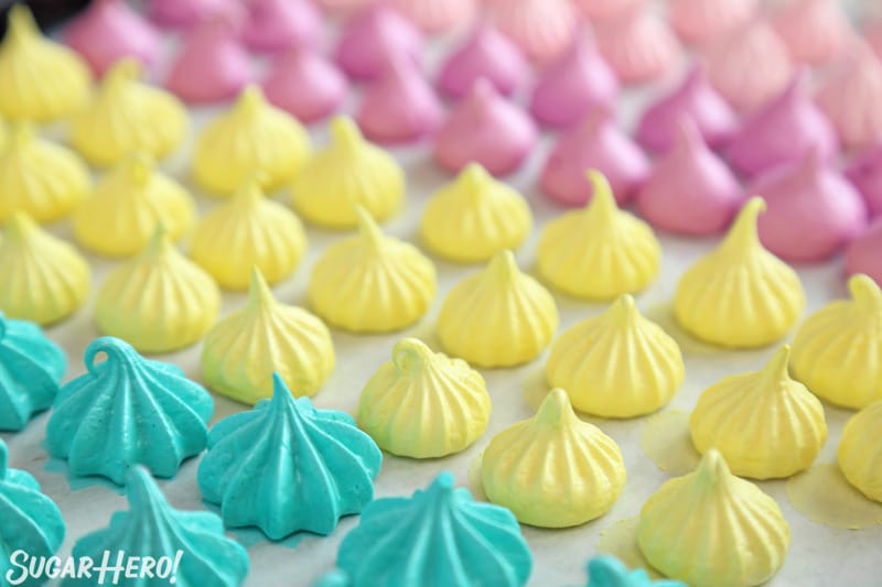 Meringue Cookies - crispy, crunchy egg white cookies that are fat-free and easy to make! | From SugarHero.com Colorful baked meringue kisses lined up on a baking sheet
