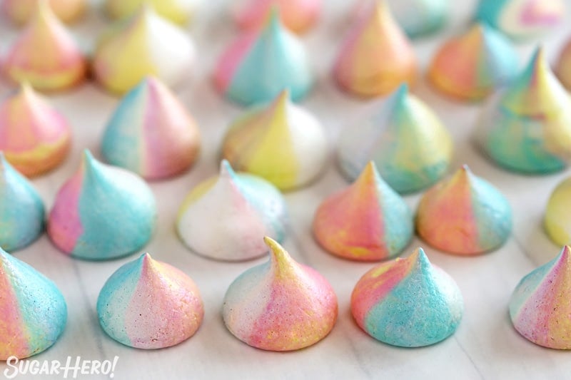 Unicorn meringues with colors swirled together lined up on a piece of parchment paper