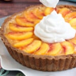 Close up of the top of a Fresh Peach Tart. with a large dollop of whipped cream.