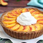 Close up of the top of a Fresh Peach Tart. with a large dollop of whipped cream.