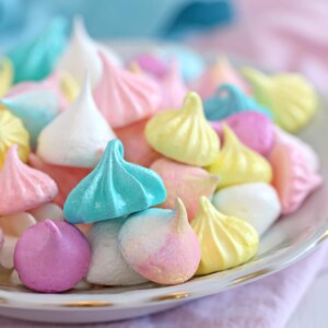 Colorful meringue cookies in assorted shapes and sizes in a bowl.
